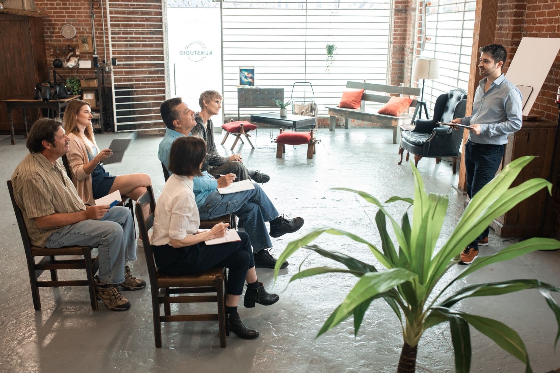 A small group seated in a workshop, listening to someone presenting